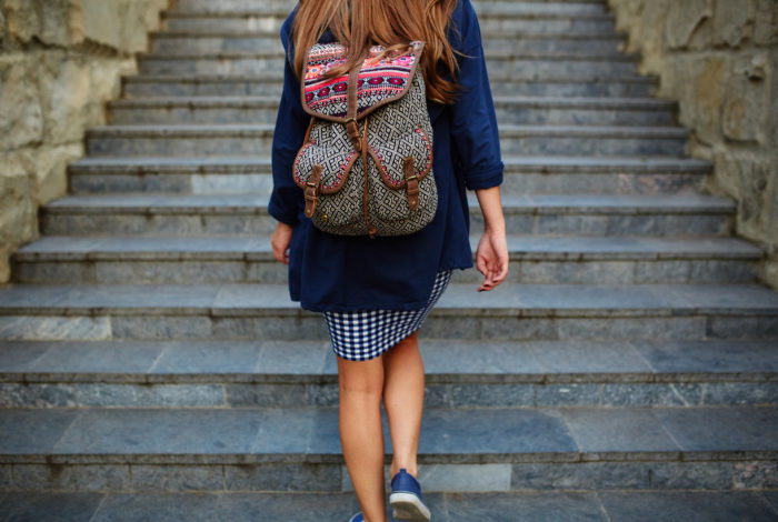Student girl with a backpack climbing stairs Student girl with a backpack climbing stairs. Rear view